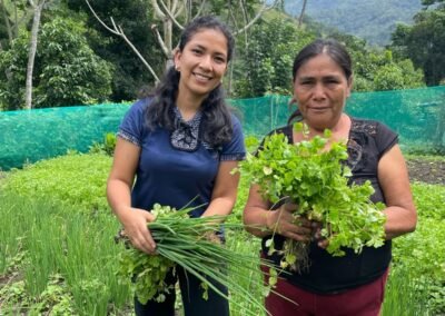 Dos productoras muestran hortalizas frescas cosechadas en el biohuerto