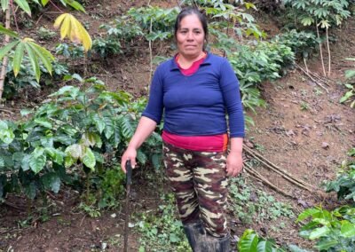 Productora de AMEP de pie entre plantas de café en su parcela