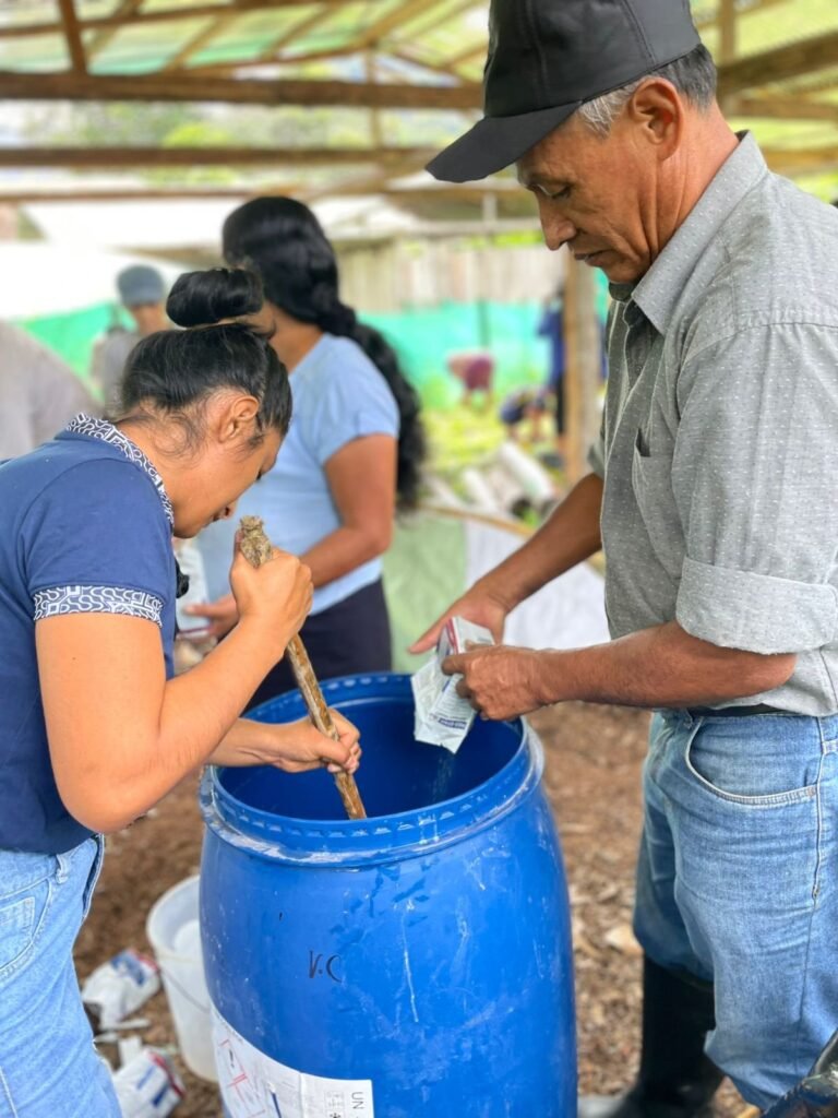 Socias preparan biol mezclando insumos orgánicos en un cilindro